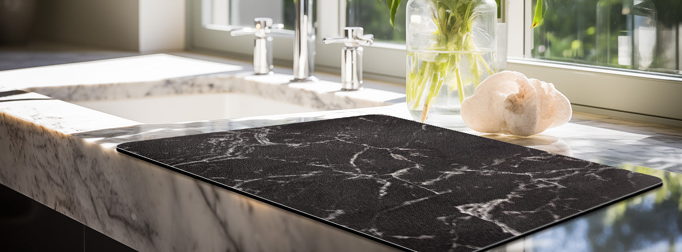 A clean kitchen sink is lined with Matace coffee mat---- marble.